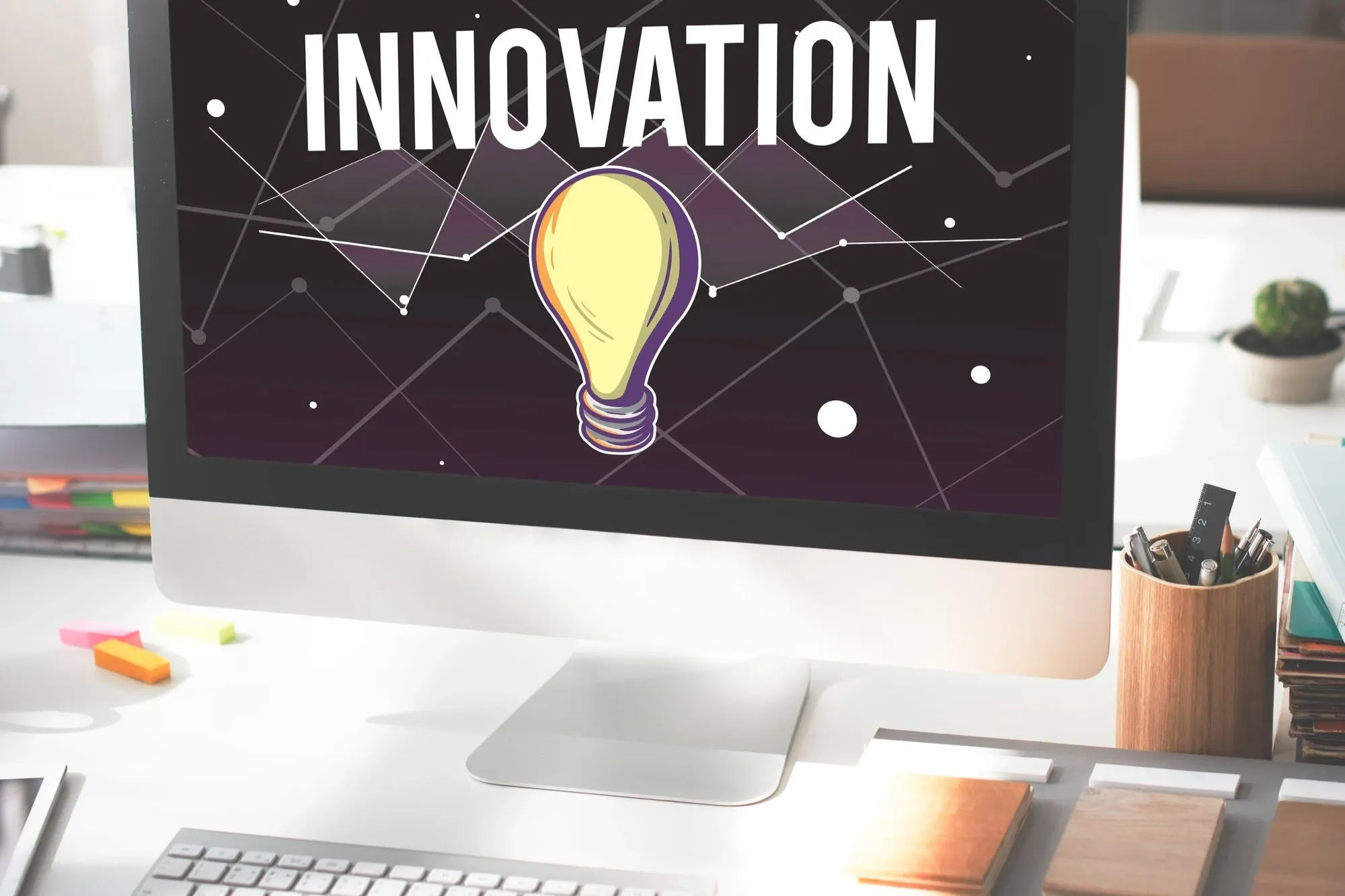 Pantalla de computadora que muestra la palabra 'INNOVATION' y una bombilla en un fondo gráfico.